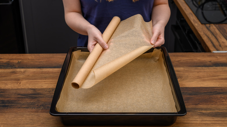 Hands lining a pan with brown paper