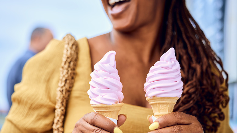 Woman holding two cones of pink soft serve ice cream