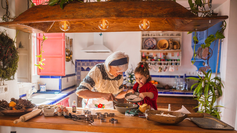 A grandma cooking in a rustic kitchen with her granddaughter.