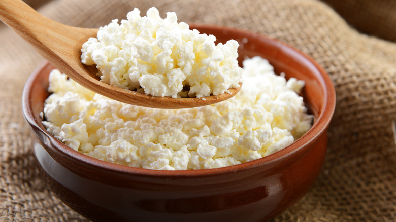 Cottage cheese with curds in a clay pot with a wooden spoon