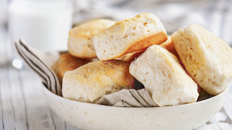Pile of buttermilk biscuits in a light bowl with a beige napkin