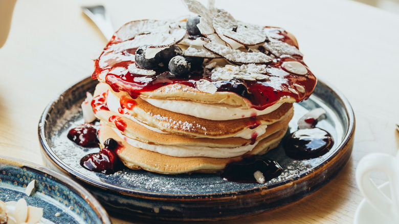 A stack of pancakes on a plate with blueberry syrup