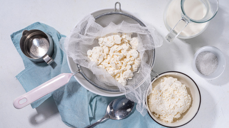 Cottage cheese being strained through a sieve and cheesecloth