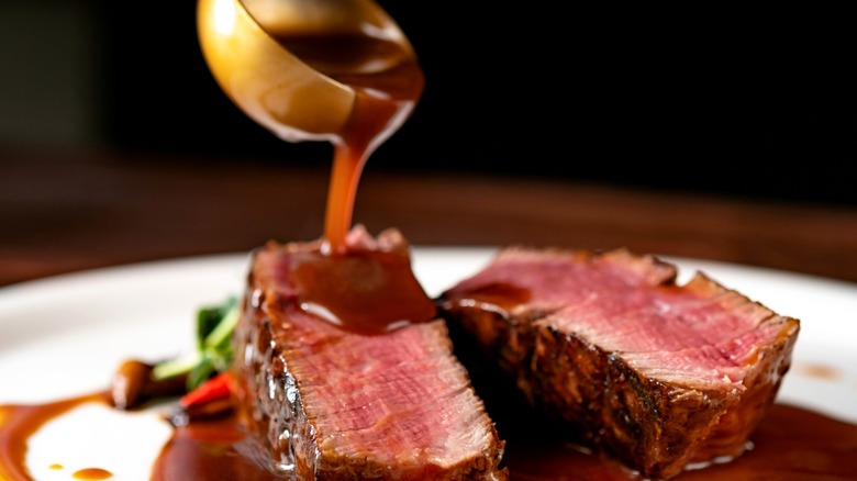 Sauce being ladled over cut steak