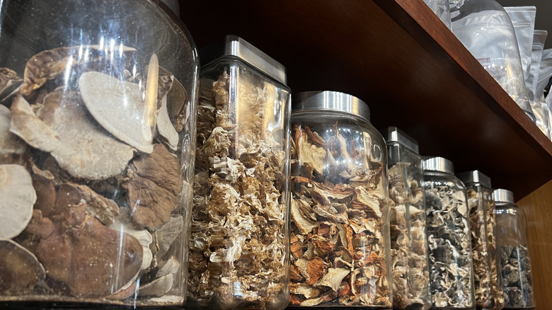 Glass jars filled with various dried mushrooms and vegetables