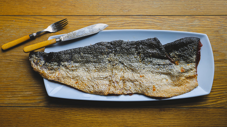 Dried salmon skin on a plate with a knife and fork