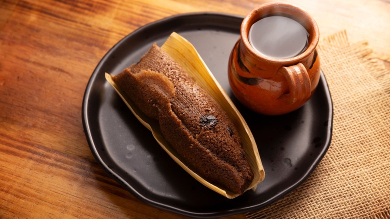 Homemade Mexican tamale on a plate with a hot drink