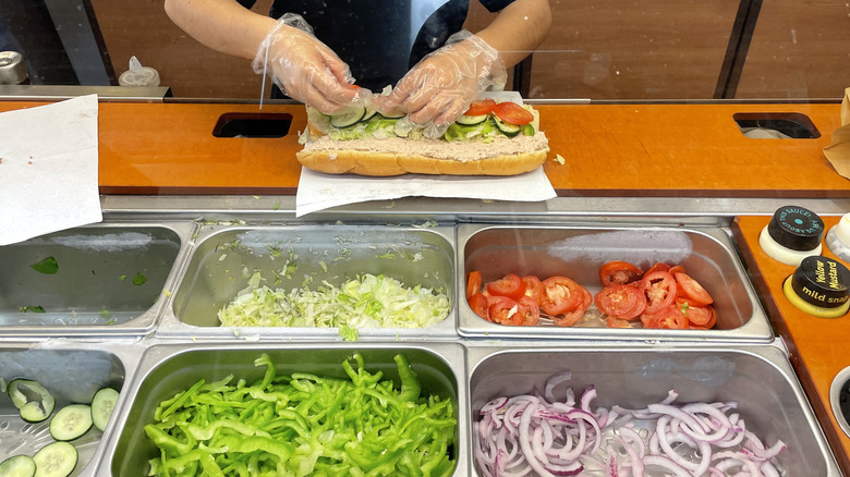 Subway employee assembling a tuna sandwich