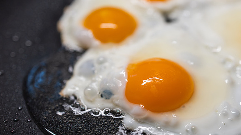 Close up of fried eggs cooking in nonstick pan with water