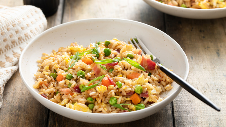 Breakfast fried rice with bacon, carrots, peas, green onions, and scrambled eggs.