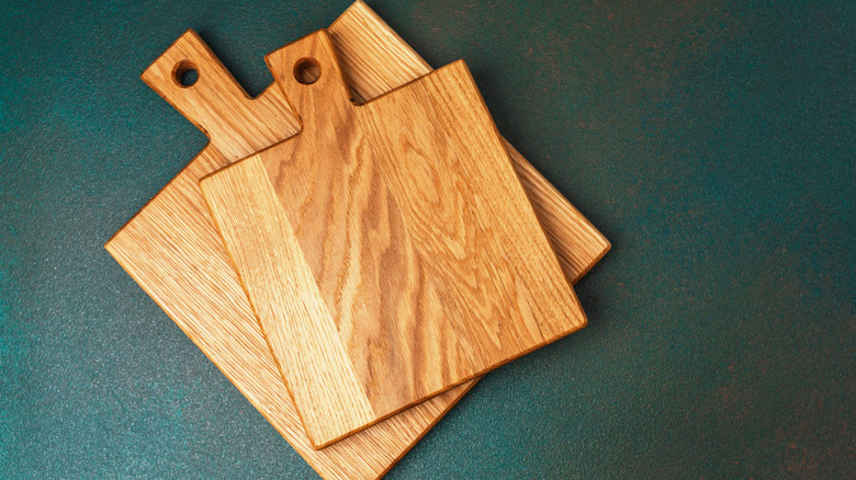Two wooden cutting boards of different sizes resting on a dark green surface.