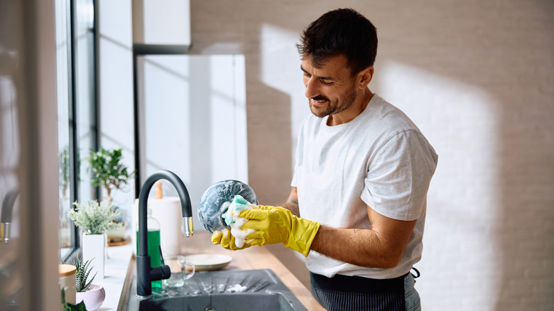 A man happily doing dishes, because he's delusional