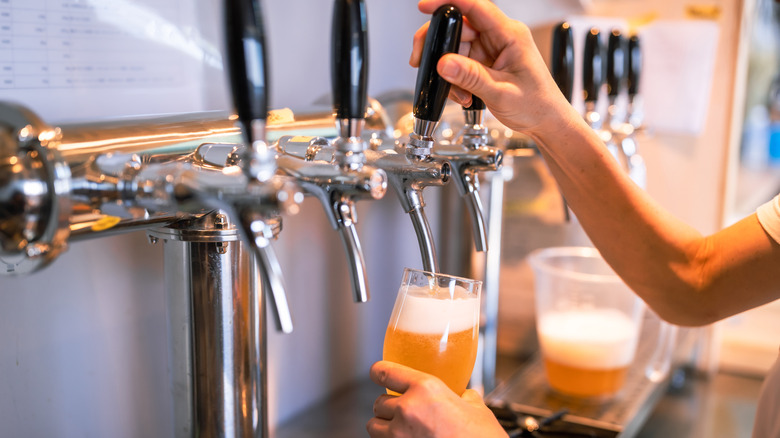 Hand filling glass with beer from a tap