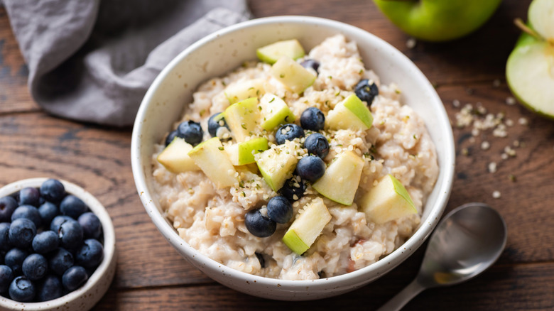 Bowl of creamy oatmeal topped with apples and blueberries