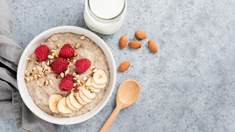 Bowl of oatmeal with raspberries, bananas, almonds, and glass of milk