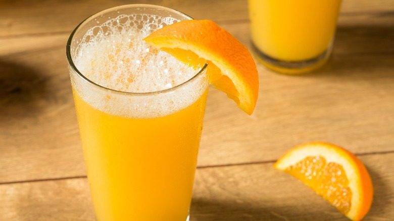 A beermosa with an orange garnish in pint a glass