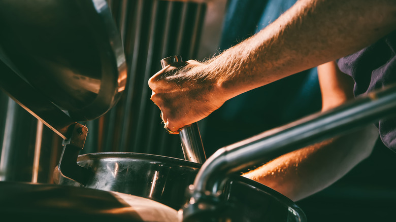Hands attending to brewery vat