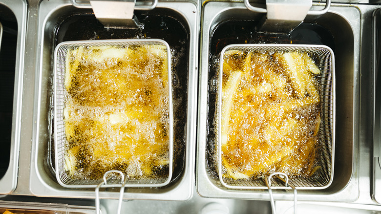 Two batches of fries cooking in deep friers