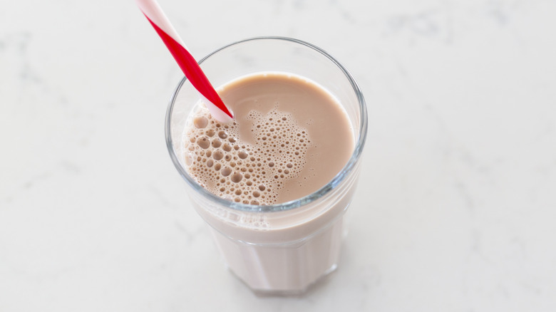A glass of chocolate milk with a red and white striped straw