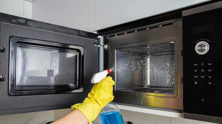 Hands cleaning a microwave.