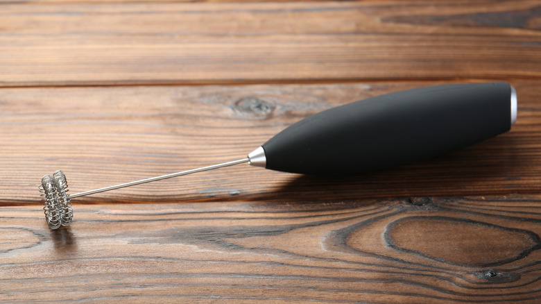 Black milk frother wand on wooden table