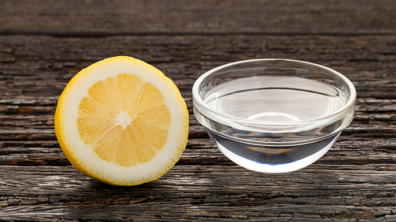 Half lemon next to small bowl of clear liquid