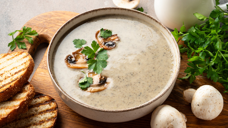 Bowl of mushroom soup with parsley and sliced mushroom garnish