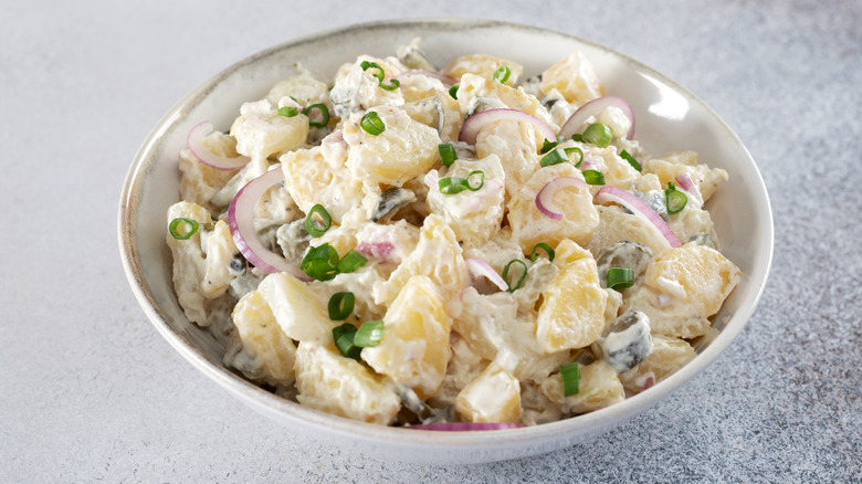 Bowl of potato salad with scallions and red onions