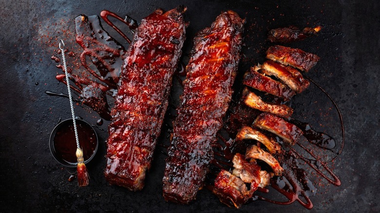 Two racks of BBQ ribs and spare ribs with sauce and basting brush