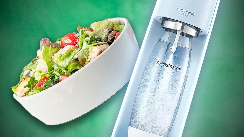 White bowl filled with salad next to SodaStream machine all in front of emerald green background