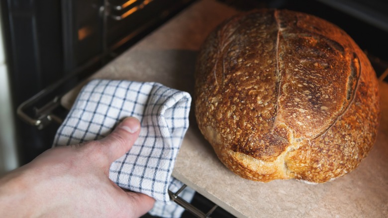 Person taking bread out of oven with kitchen towel