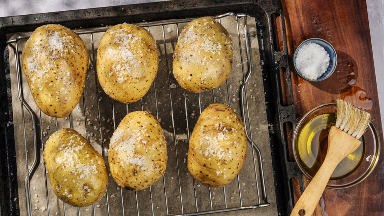 Seasoned potatoes on a rack with a baking sheet underneath