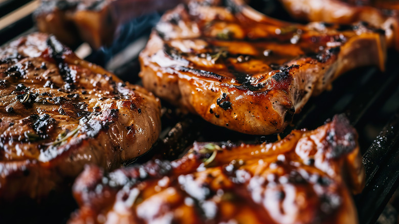 A close-up of pork chops cooking on the grill