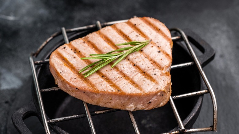 Seared tuna steak on grate with rosemary sprig on top