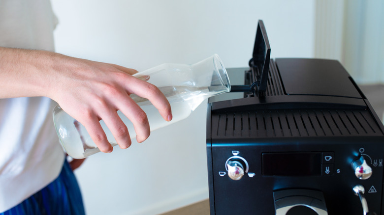 Someone pouring water into a coffee maker.