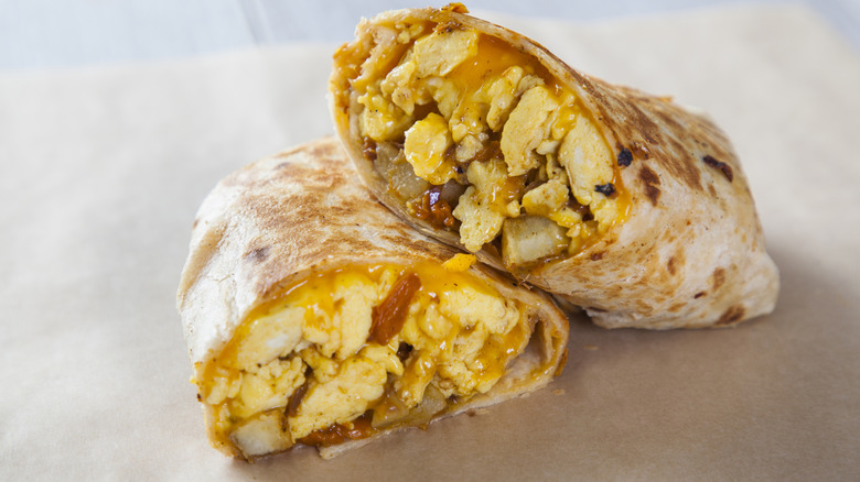 Halved breakfast burrito filled with eggs, melted cheese, and potatoes