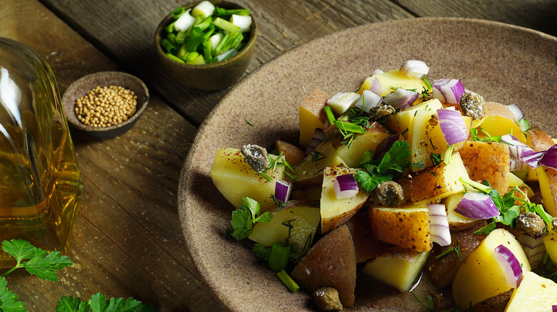 Plate of potato salad with mustard dressing and a pot of mustard seeds
