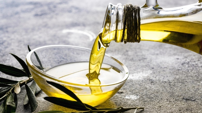 Olive oil being poured into a glass bowl