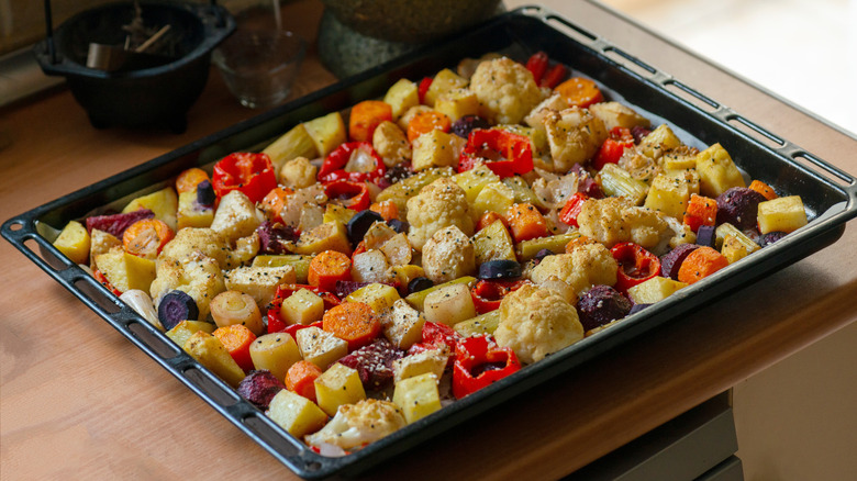 A tray of seasoned vegetables resting on a wooden countertop
