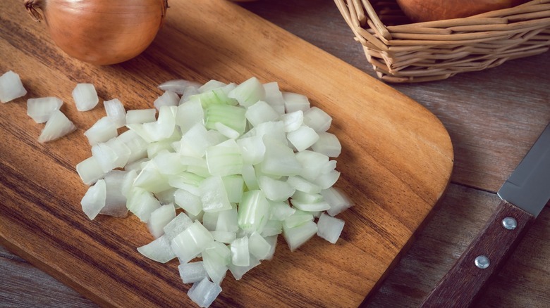 Chopped and whole onions on wood cutting board