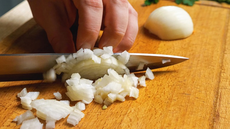 Person cutting onions on wood cutting board