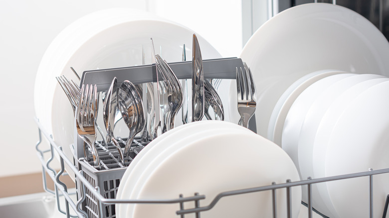 Clean cutlery and plates in a dishwasher.